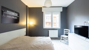 A bedroom with a bed, a chair, a TV, a window, and a wall-mounted picture. - Mascarella (Bologna)