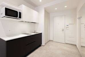 Eine moderne Küche mit Einbau-Mikrowelle, Spüle und dunklen Schränken.