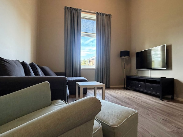 Ein Wohnzimmer mit einer Couch, einem kleinen Tisch, einem Fernseher und einer Lampe.
