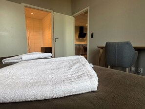 A hotel room with a bed, a chair, and a bathroom visible through an open door.