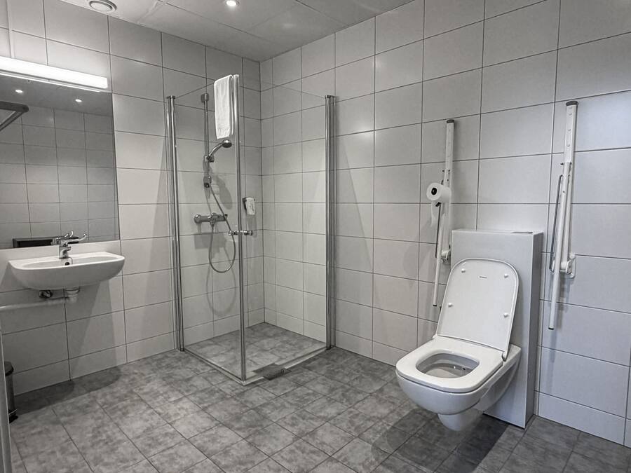 Un baño moderno con ducha, inodoro, lavabo y espejo.