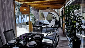 An outdoor patio with a dining table set for four, a cushioned seating area, and a potted plant. - Mobile Home Saky, Camp Soline (Biograd na Moru)