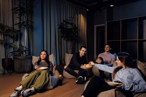 A group of people sitting on sofas in a room with a large window, a plant, and a potted plant. - Student Only Arch View House (Wembley)