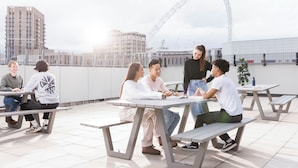 Une terrasse sur le toit avec des sièges en plein air, une grande roue en arrière-plan et des bâtiments modernes.