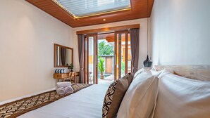 Habitación de hotel con cama, escritorio, silla, espejo y vistas al exterior.