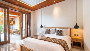 Un dormitorio moderno con una cama grande, cabecera de madera, mesitas de noche y vistas a un área exterior a través de puertas de cristal.