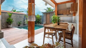 Una cocina moderna con alacenas de madera y un comedor con vista a la piscina.