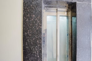 A bathroom with a granite countertop and a glass shower enclosure.