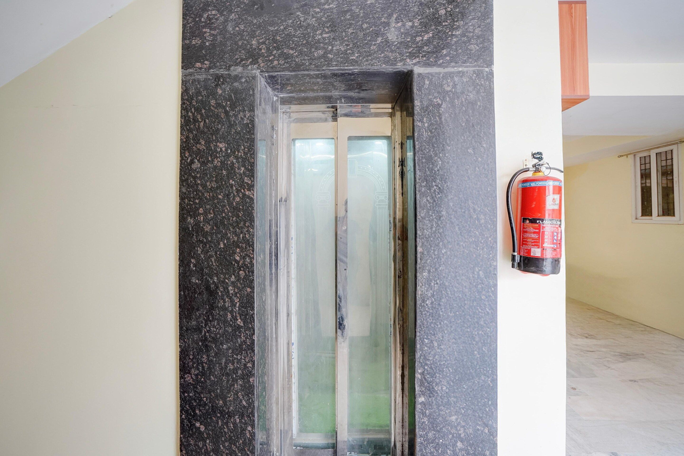 A hallway with a fire extinguisher mounted on the wall and a door with a frosted glass panel.