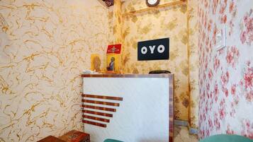 Une pièce comprenant un comptoir d’accueil, une horloge et un panneau indiquant « OYO ».