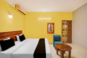 Ein Hotelzimmer mit Bett, Stuhl, einem kleinen Tisch und einer Tür mit dekorativer Verkleidung.