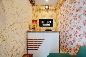 A hotel reception area with a reception desk, a clock, and a sign indicating it is serviced by OYO. - Classic Hotel Newyork (Patna)