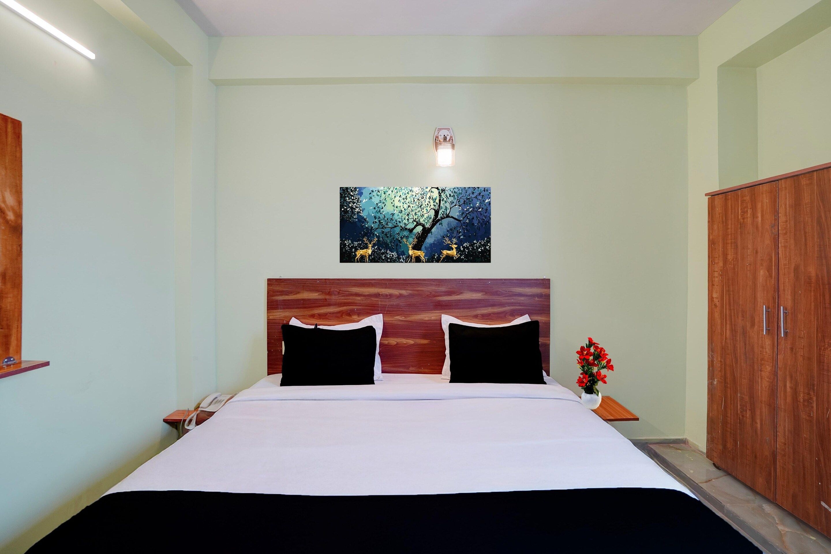 Une chambre à coucher avec un lit, une table de chevet, une lampe, une armoire et un tableau au mur.
