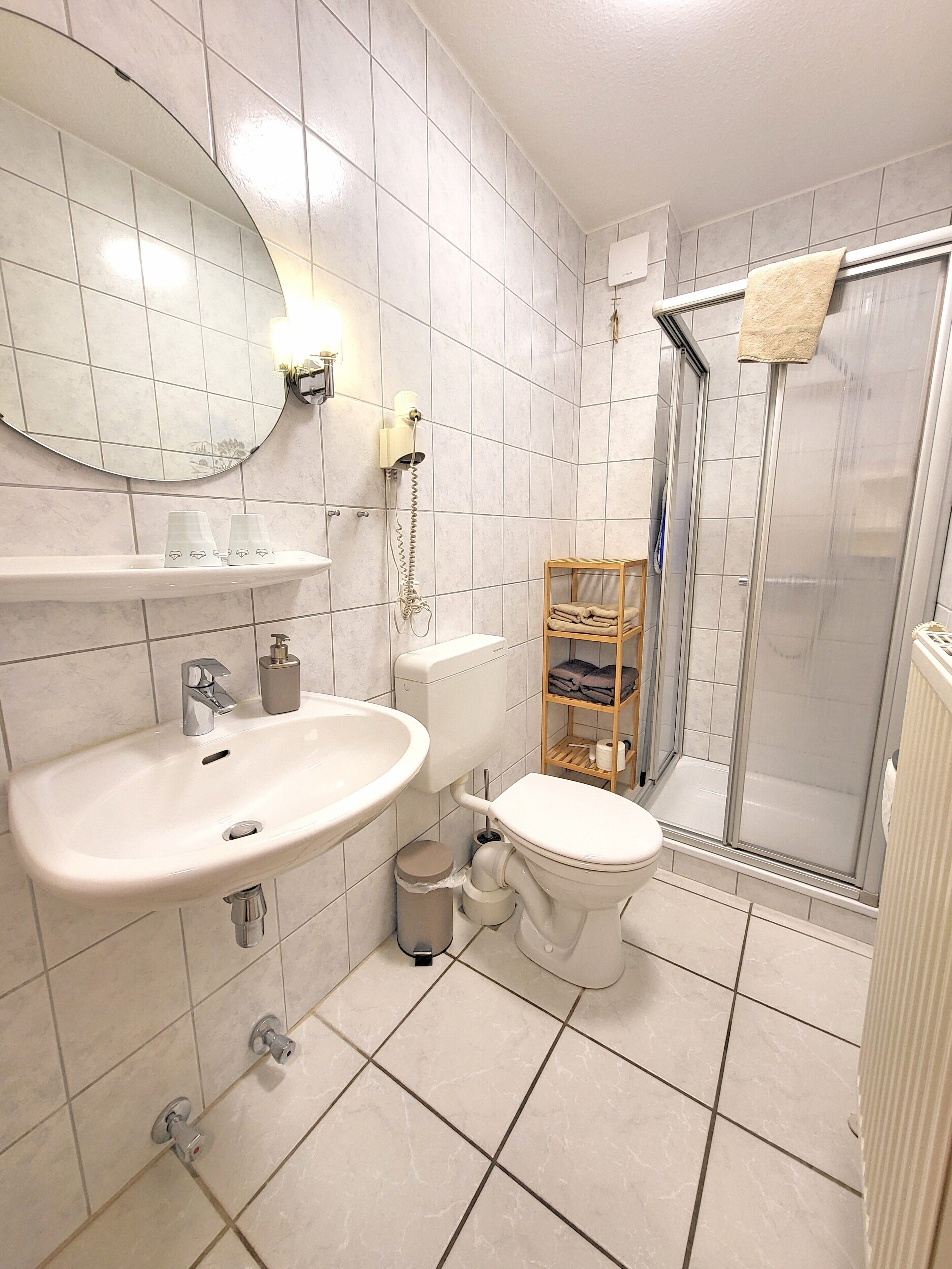 Ein Badezimmer mit Waschbecken, Toilette, Dusche und Spiegel.