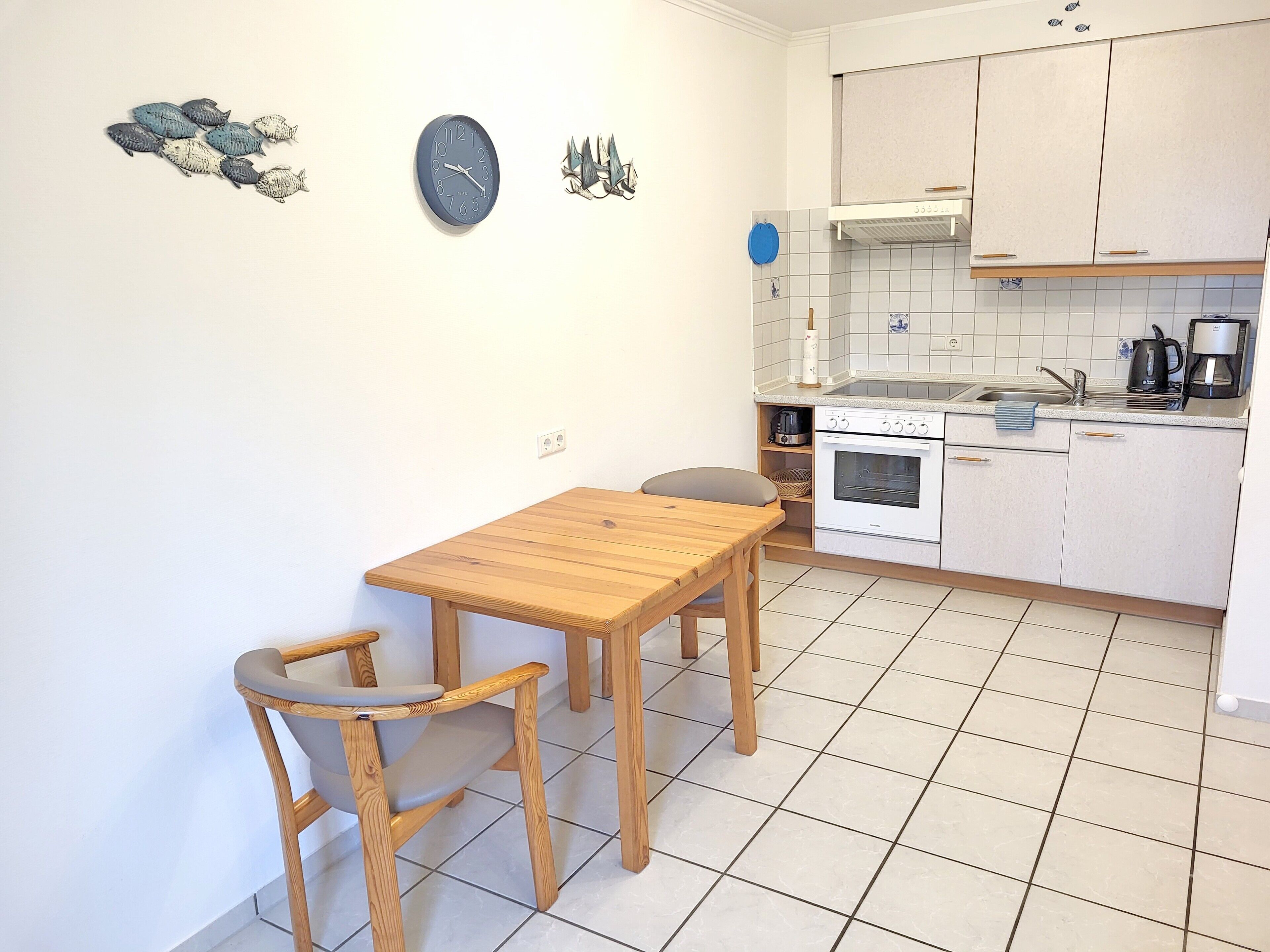 Eine kleine Küche mit Holztisch und -stühlen, einem weißen Backofen und einer Kaffeemaschine.