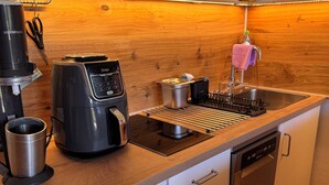 Eine kompakte Küche mit Kaffeemaschine, Wasserkocher, Geschirrgestell und Geschirrspüler.