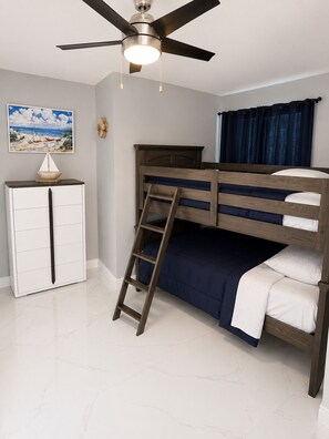A bunk bed with a ladder, a desk, and a ceiling fan in a room with a painting on the wall. - 4-bedroom house in perfect Cocoa with cool AC for relaxing stays (Cocoa)