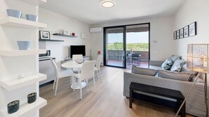 A modern living space with a dining area, a sofa, and a balcony with a view.