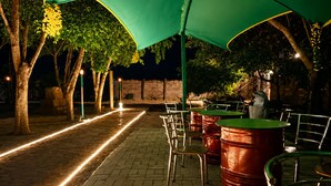 An outdoor seating area with tables and chairs, a brick pathway, and trees.