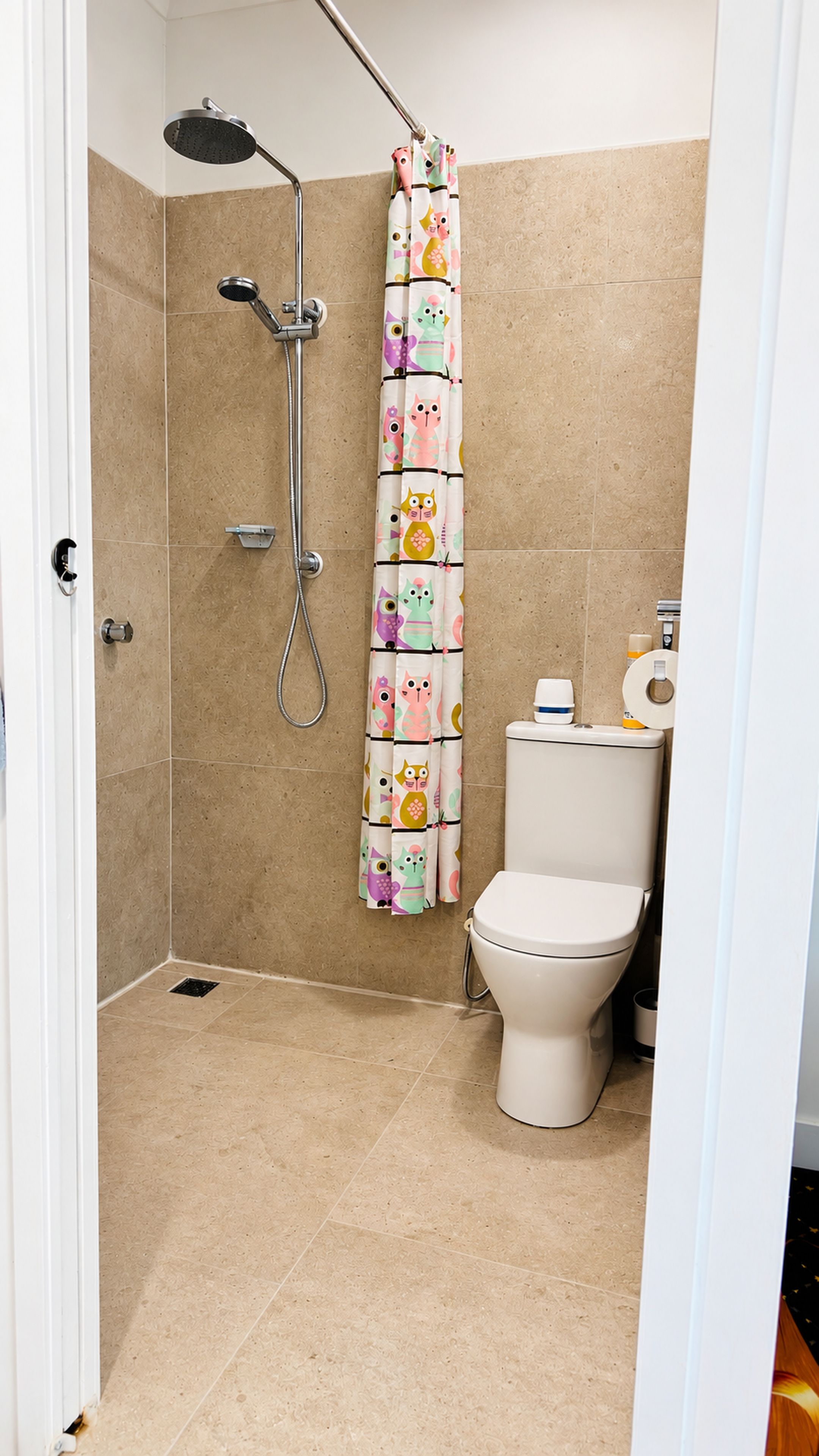 A bathroom with a shower, toilet, and a curtain with animal prints.