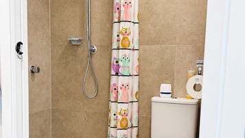 A bathroom with a shower, toilet, and a curtain with animal prints.