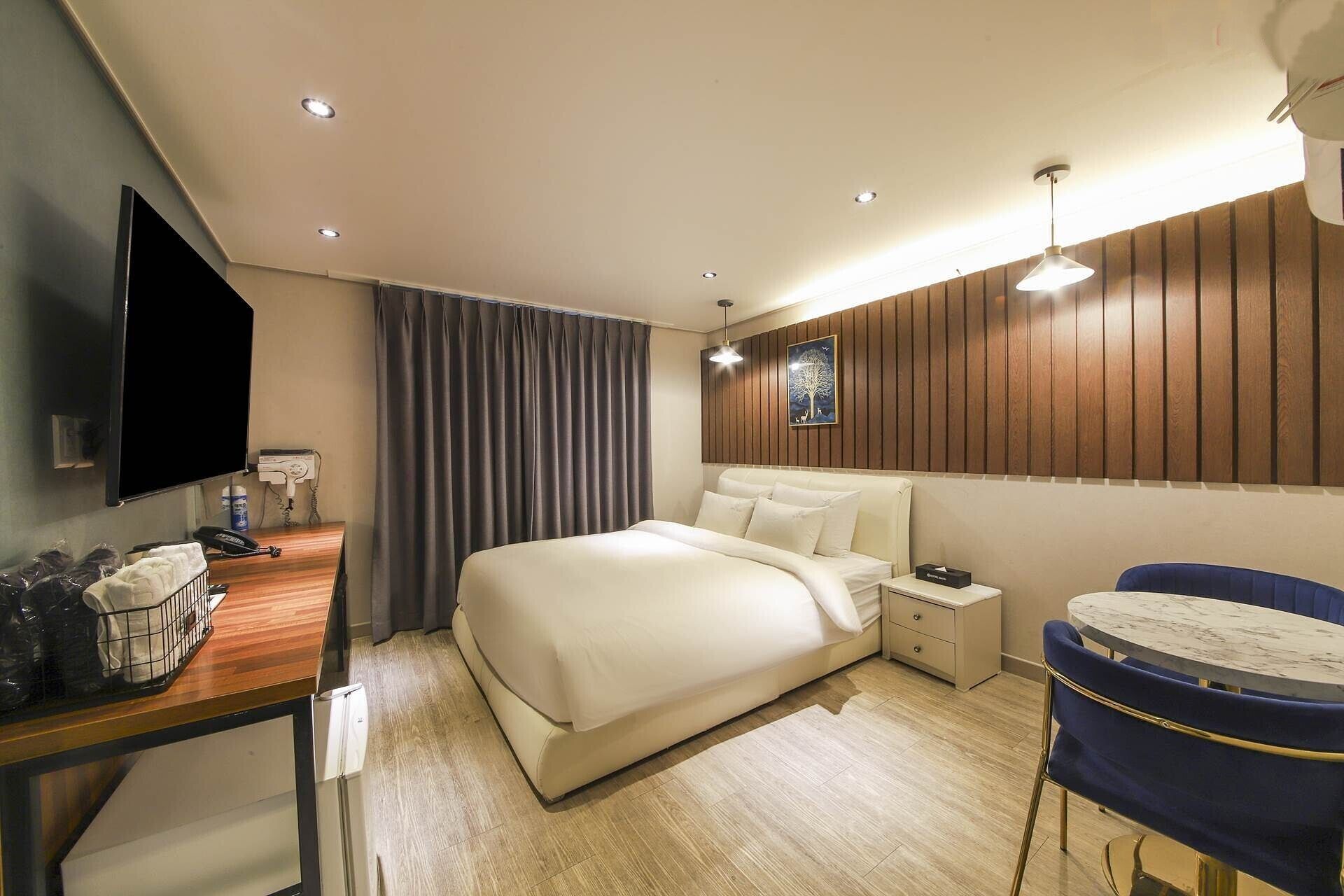 Una habitación de hotel con cama, mesita de noche, lámpara y escritorio con silla.