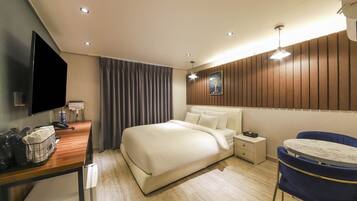 Una habitación de hotel con cama, mesita de noche, lámpara y escritorio con silla.