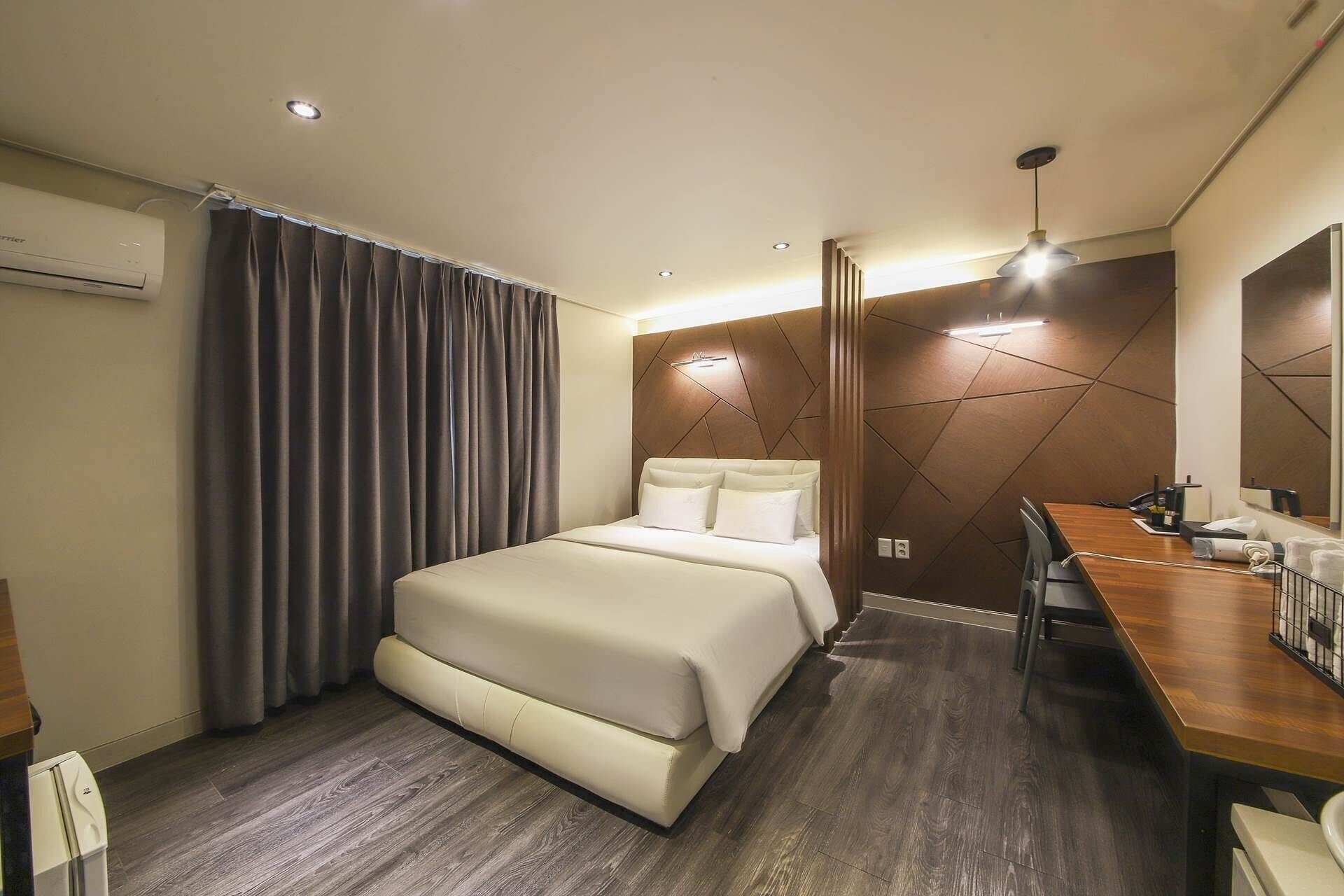Une chambre d’hôtel avec un lit, un bureau et un miroir.