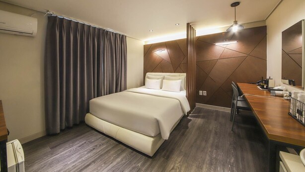 Une chambre d’hôtel avec un lit, un bureau et un miroir.