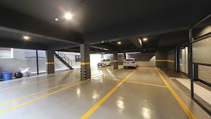 Un parking à plusieurs niveaux, doté de marquages au sol bien visibles pour délimiter les voies et d’un escalier menant à un niveau supérieur.