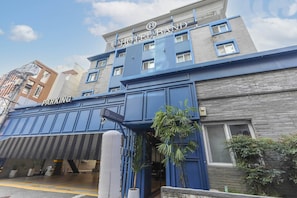 A hotel building with a prominent 'HOTEL BAND' sign, a parking area, and a gated entrance.