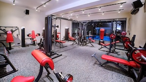 A gym with various exercise equipment, including weight machines and benches. - Luziana Hotels (Abuja)
