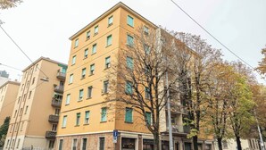 En byggnad med flera våningar, en gul fasad, många fönster och en tydligt markerad entré på bottenvåningen.