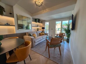 Ein modernes Wohnzimmer mit einer Couch, einem Esstisch, Stühlen und einem an der Wand befestigten Fernseher.
