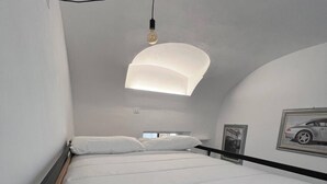 Ein Bett mit Kopfteil, eine Pendelleuchte und ein gerahmtes Bild an der Wand.