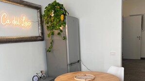 Ein moderner Essbereich mit einem runden Holztisch, weißen Stühlen, einer Neonreklame, einem Fahrrad und einer Pflanze.