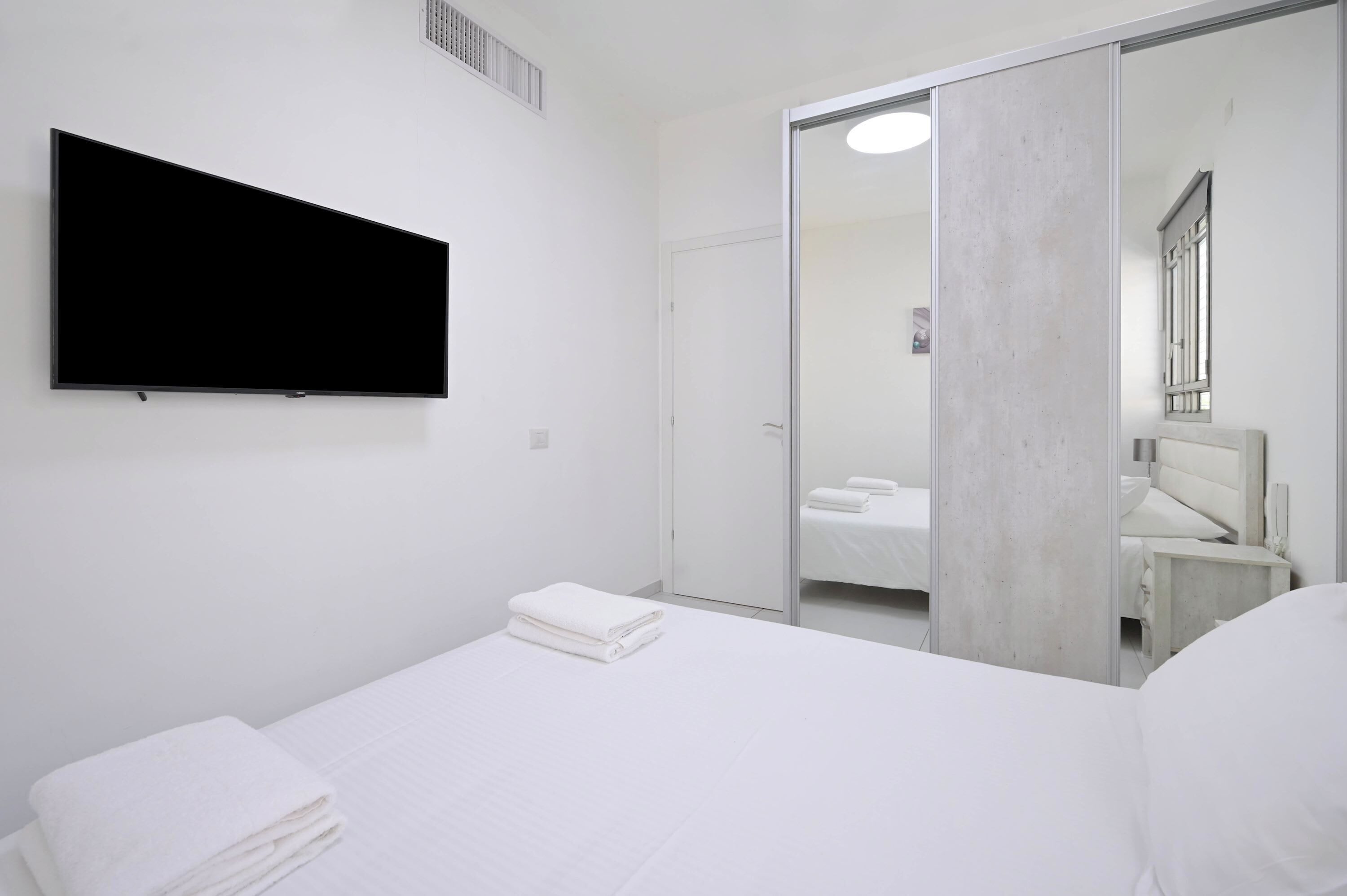 Une chambre d’hôtel comprenant un lit, un téléviseur à écran plat fixé au mur, une porte coulissante donnant accès à la salle de bain et un miroir.