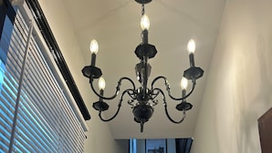Eine Treppe mit Holzdielen und einem schwarzen Geländer, die zu einer Empore mit einem Chandelier führt.