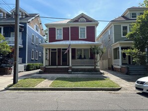 Uma casa de dois andares com varanda frontal, um pequeno jardim da frente e uma caixa de correio.