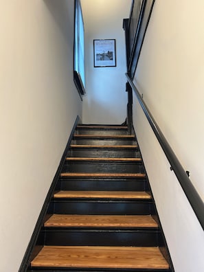 Eine Treppe mit hölzernen Stufen und schwarzen Geländern, die zu einer Empore führt, auf der ein gerahmtes Bild von Wilmington zu sehen ist.