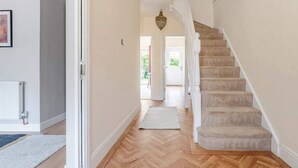 A staircase leading to a second floor, a hallway with a wooden floor, and a door leading outside. - Spacious Home near Bristol & Bath, Ideal for (Emersons Green)