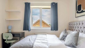 A bedroom with a bed, a desk, a chair, and a window with curtains. - Spacious Home near Bristol & Bath, Ideal for (Emersons Green)