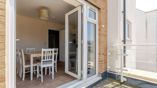 An open sliding glass door leading to a dining area with a table and chairs. - Spacious Home near Bristol & Bath, Ideal for (Emersons Green)