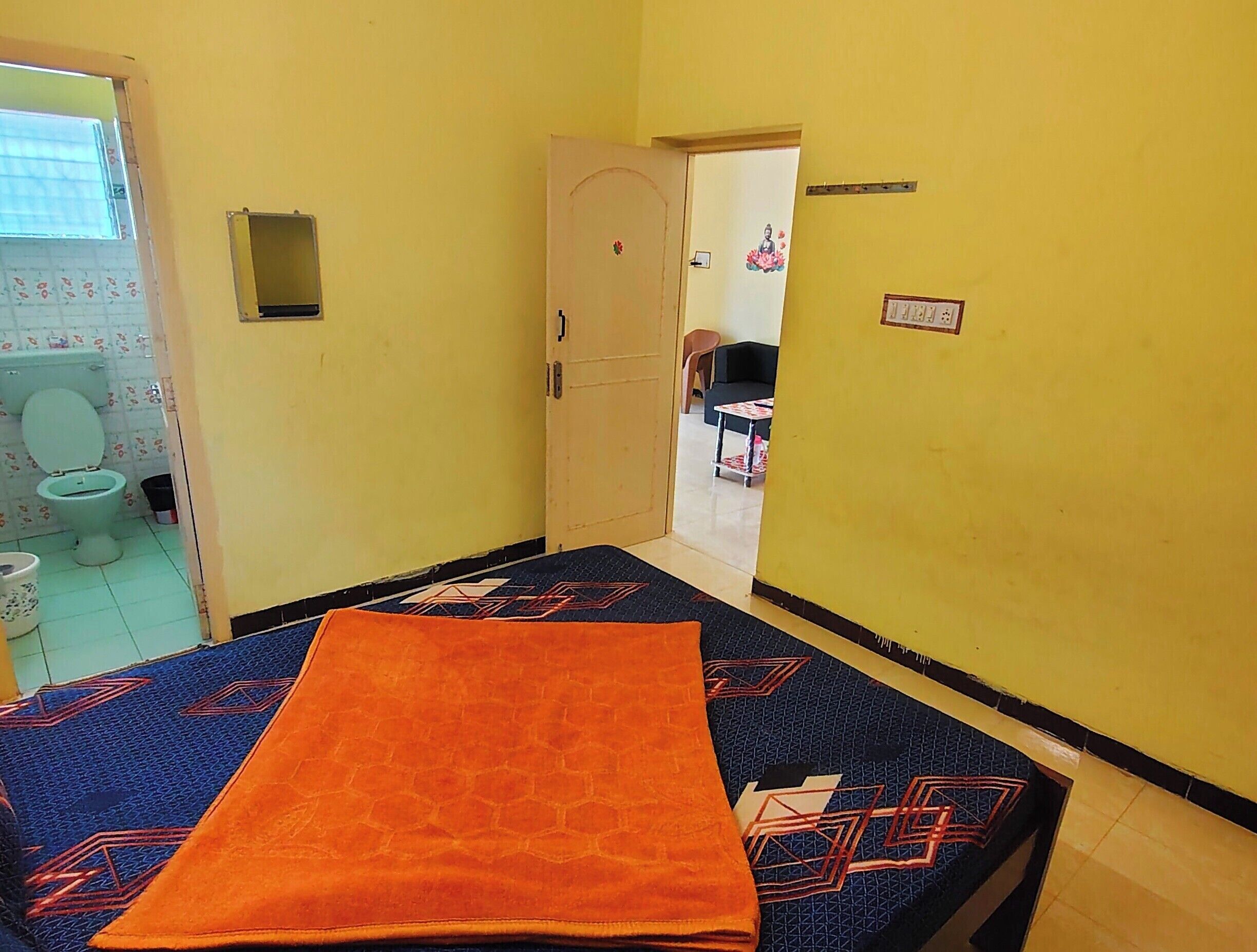 A room with a bed, a door leading to a bathroom, and a small table with a chair.