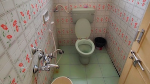 A small bathroom with a toilet, shower, and a window.