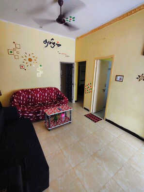 A living room with a sofa, a ceiling fan, and decorative wall art.