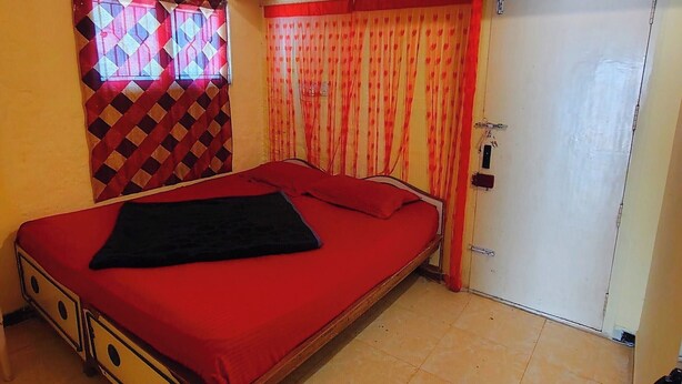 A bedroom with a single bed, a ceiling fan, a window with patterned curtains, and a closed door. - AKS Cottage (Salem)