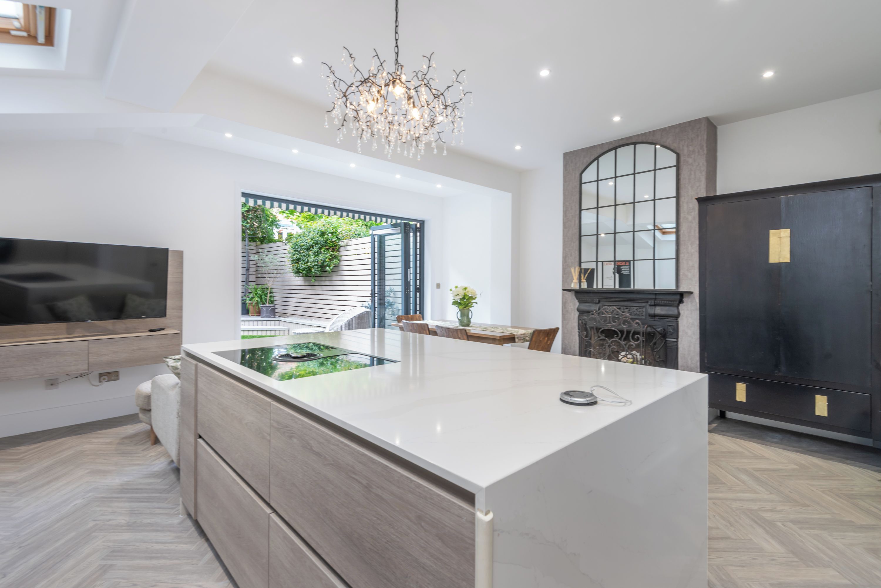 A modern kitchen with a central island, a dining area with a table and chairs, and a built-in TV.