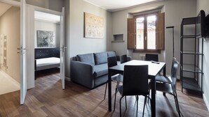 Ein modernes Interieur mit einer Couch, einem Esstisch, Stühlen, einem Heizkörper und einem Fenster.