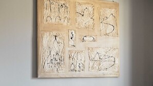 Ein Zimmer mit grauem Sofa und einem strukturierten Kunstwerk an der Wand.
